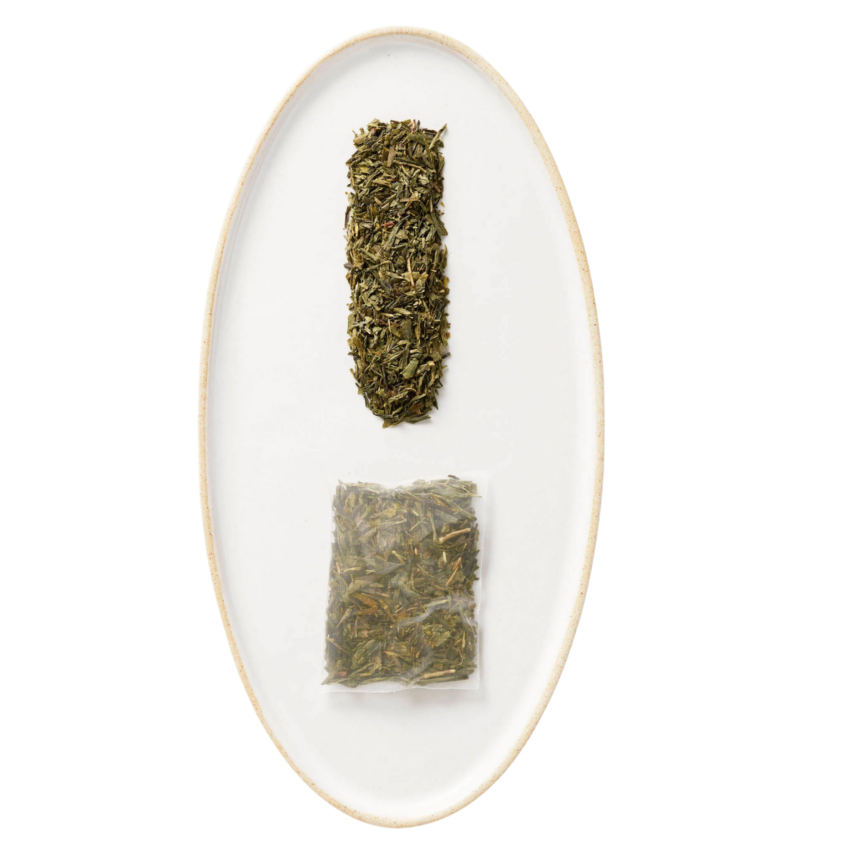 Two tea leaves on a white oval plate with a gold rim against a white background