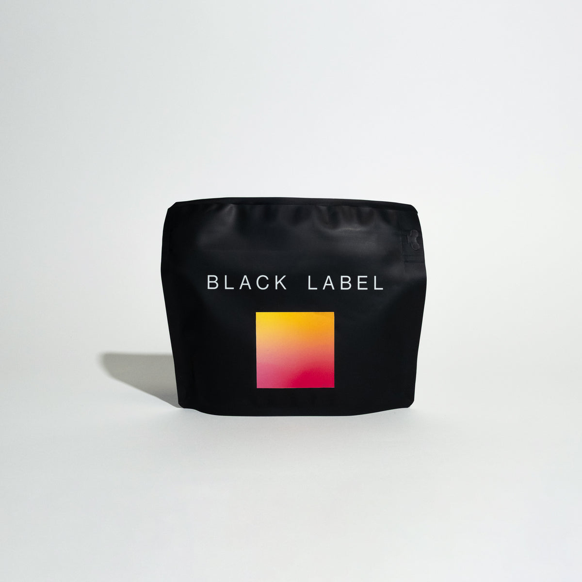 Matte-black stand-up pouch labeled BLACK LABEL with gradient square graphic, promoting coffee R - Gesha Village - Lot 50, emphasizing producer trust and sipping experience.