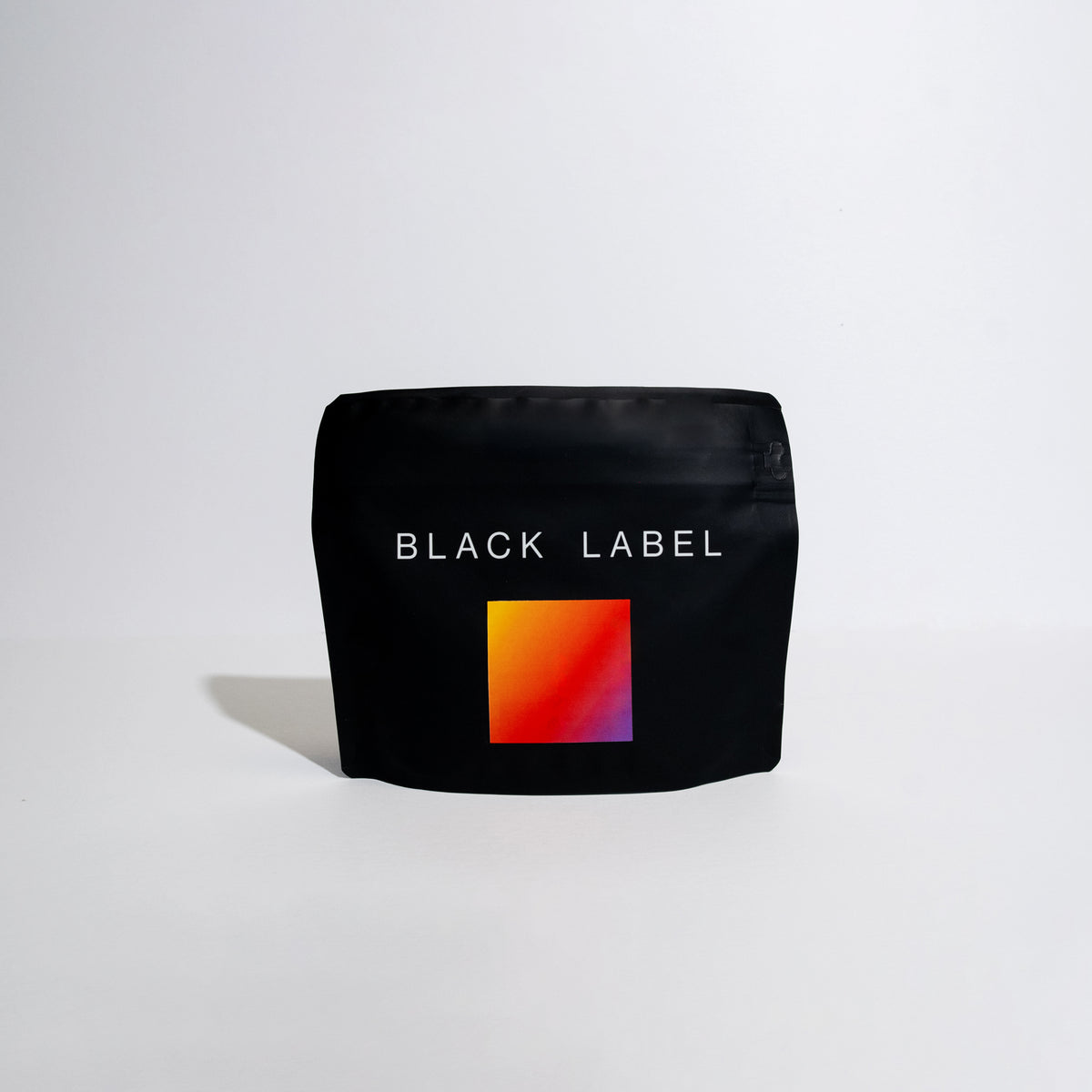 A black bag of coffee on a white background with a colorful label and the words Black Label on it. This coffee is Finca Deborah Symbiosis.