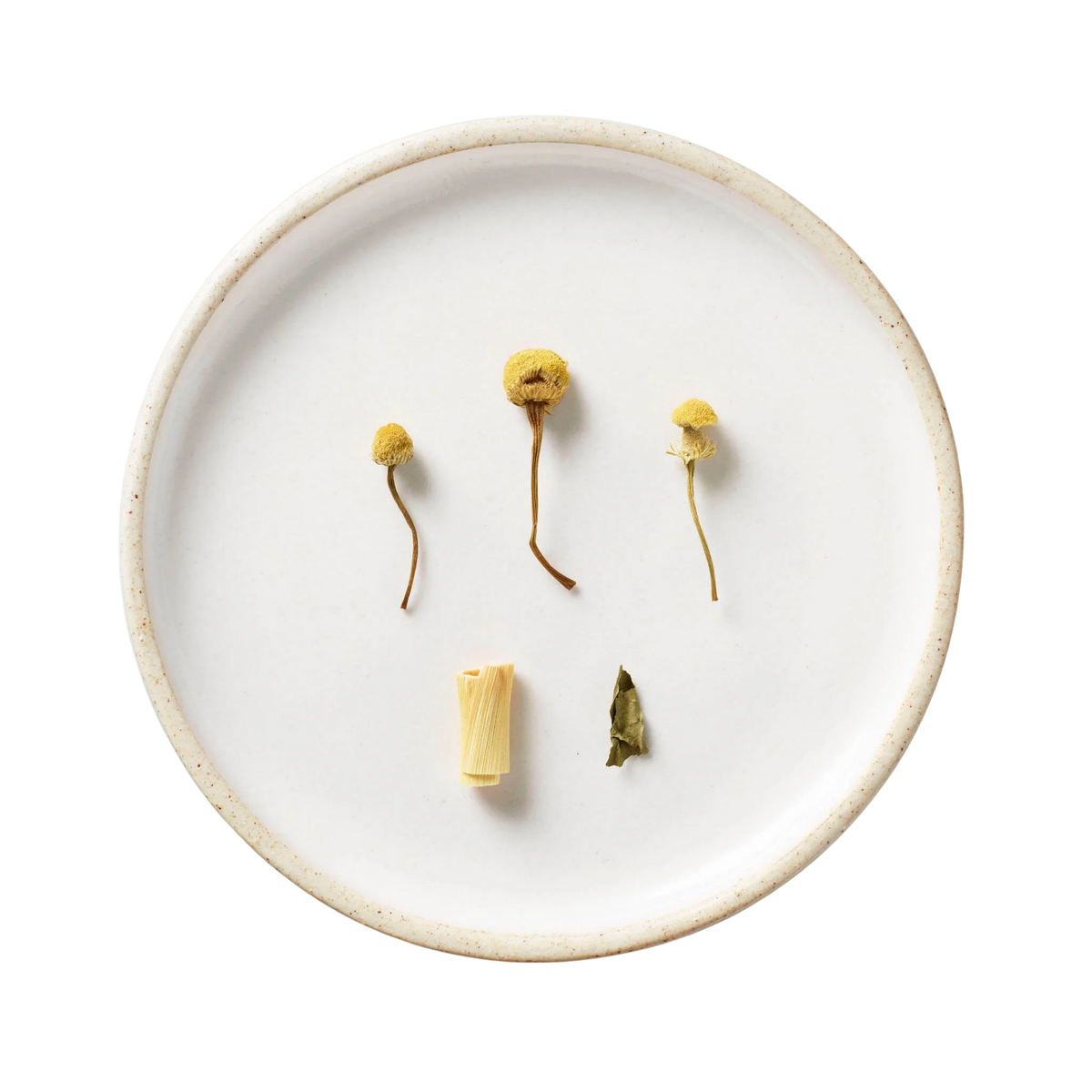 Bouquet | Tisane Blend: Overhead view of chamomile flowers, lemongrass, and a dried leaf, showcasing the key ingredients of this honey-sweet, caffeine-free tisane.