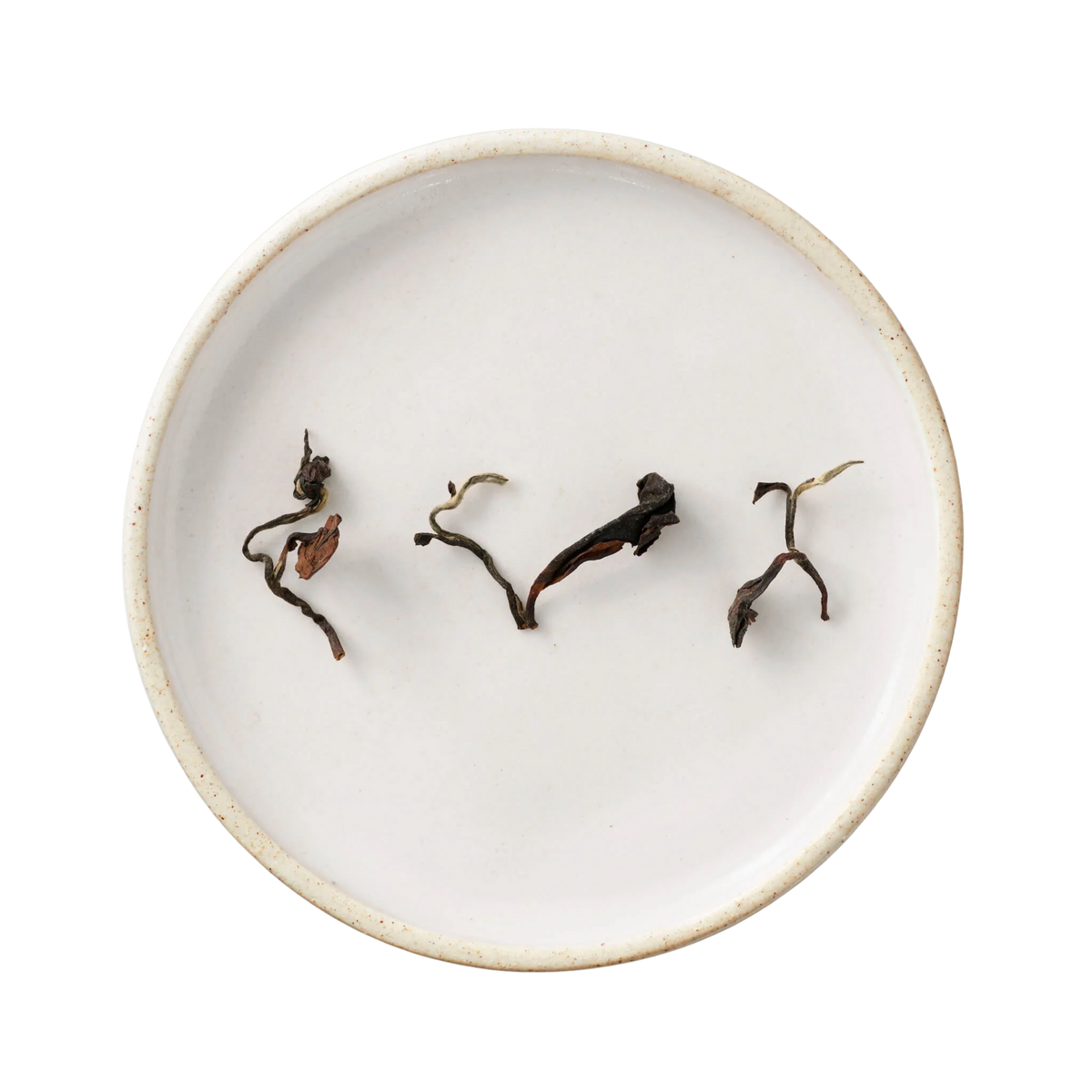 Champagne Long Kou Oolong: A white ceramic dish holds twisted, dark-brown dried leaves of Eastern Beauty tea, showcasing its rich, layered aroma.