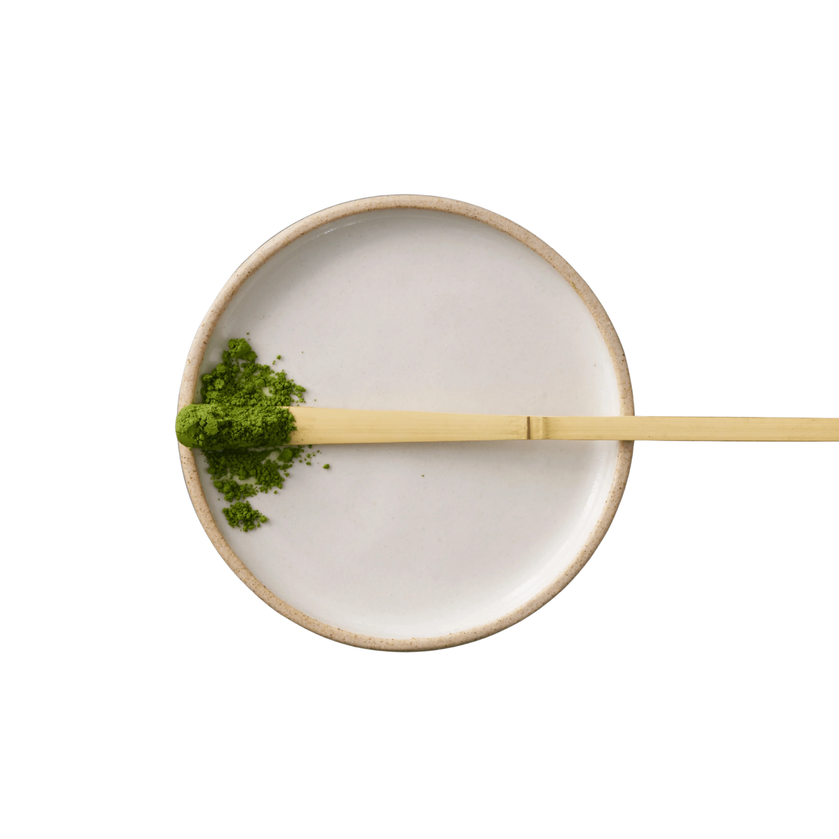 White ceramic bowl with matcha powder and a gold spoon on a white background