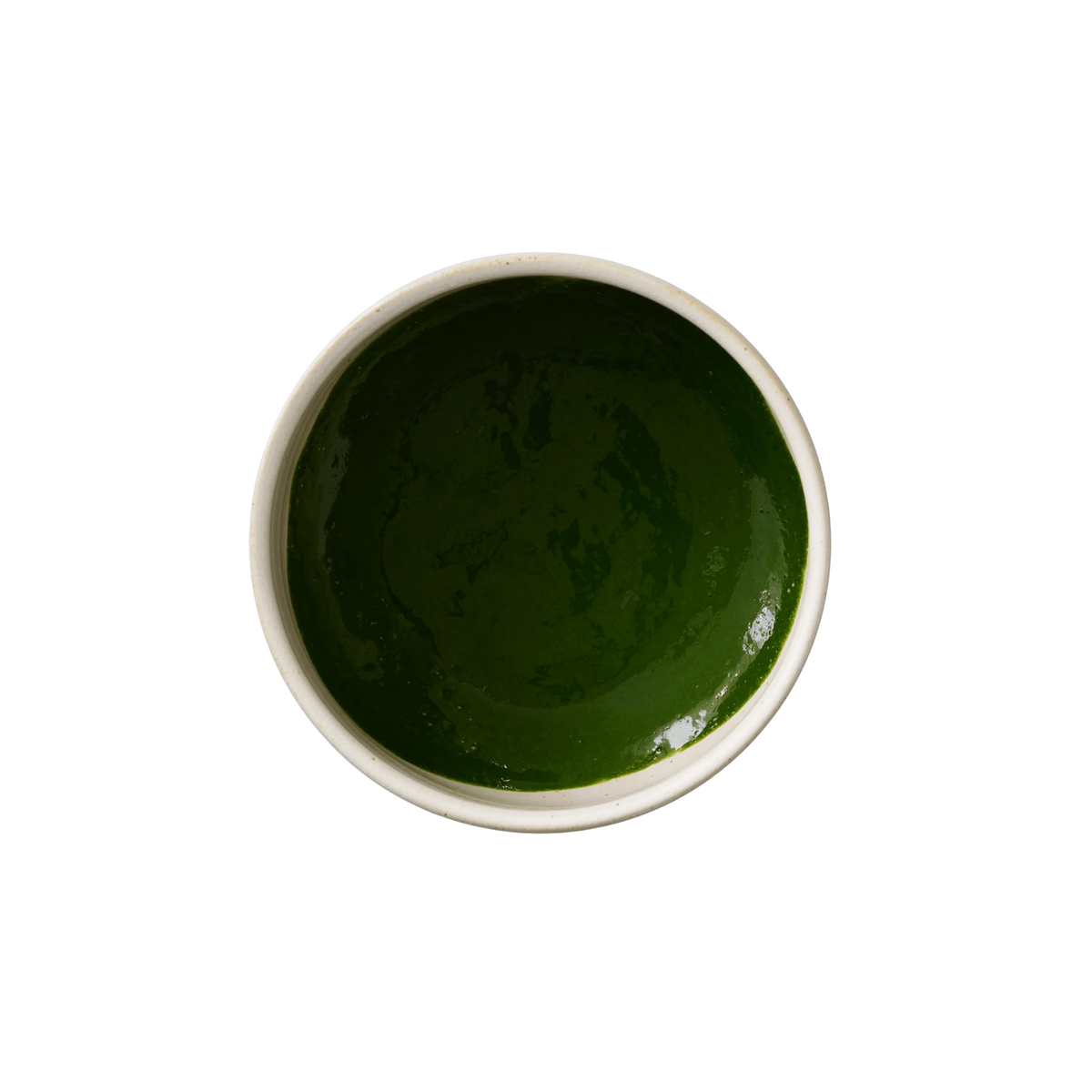 Top-down view of a bowl filled with matcha liquid on a white background