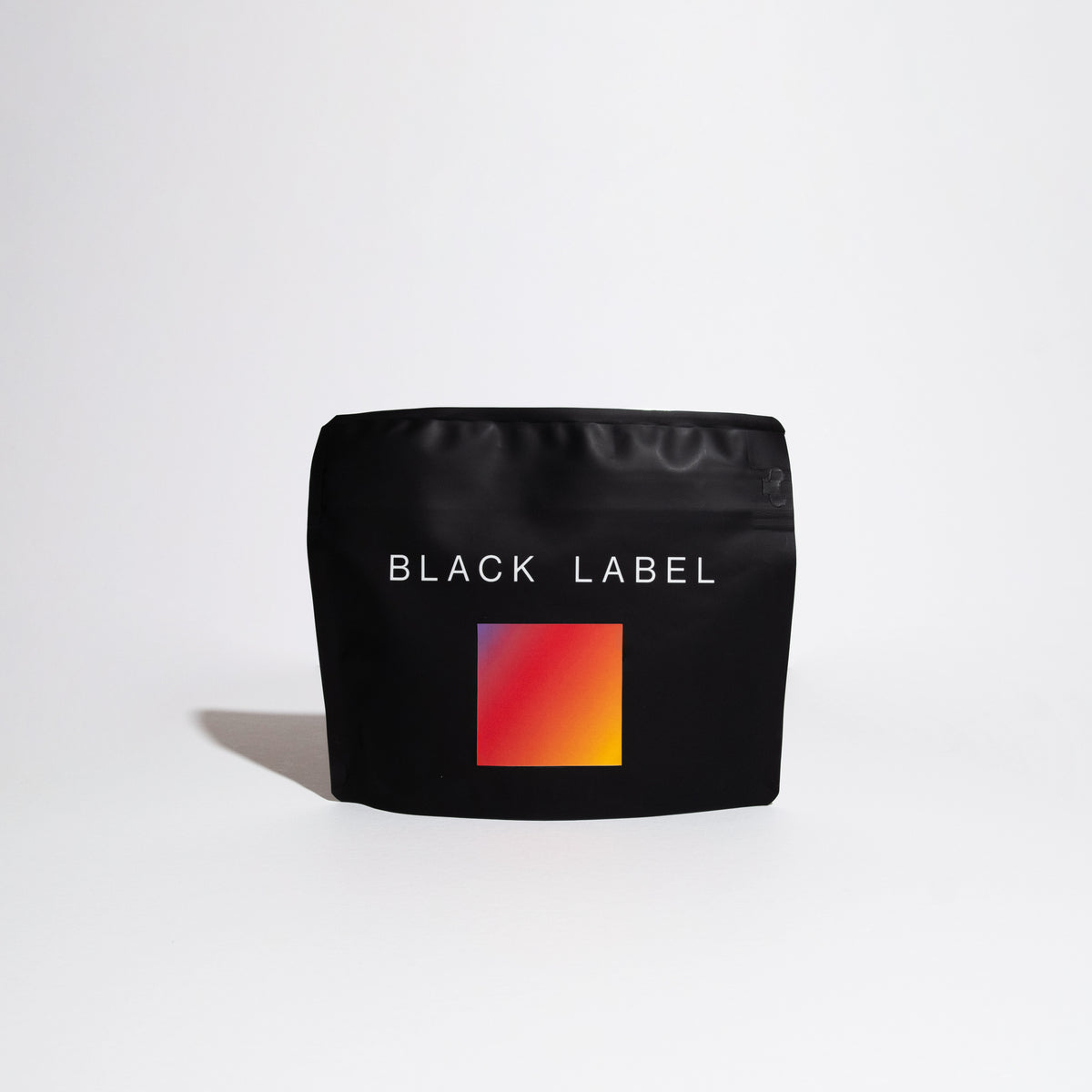 Matte-black pouch labeled BLACK LABEL with red-to-orange swatch, representing Finca Deborah Symmetry coffee. Showcases top-tier Panamanian Gesha production by Jamison Savage.