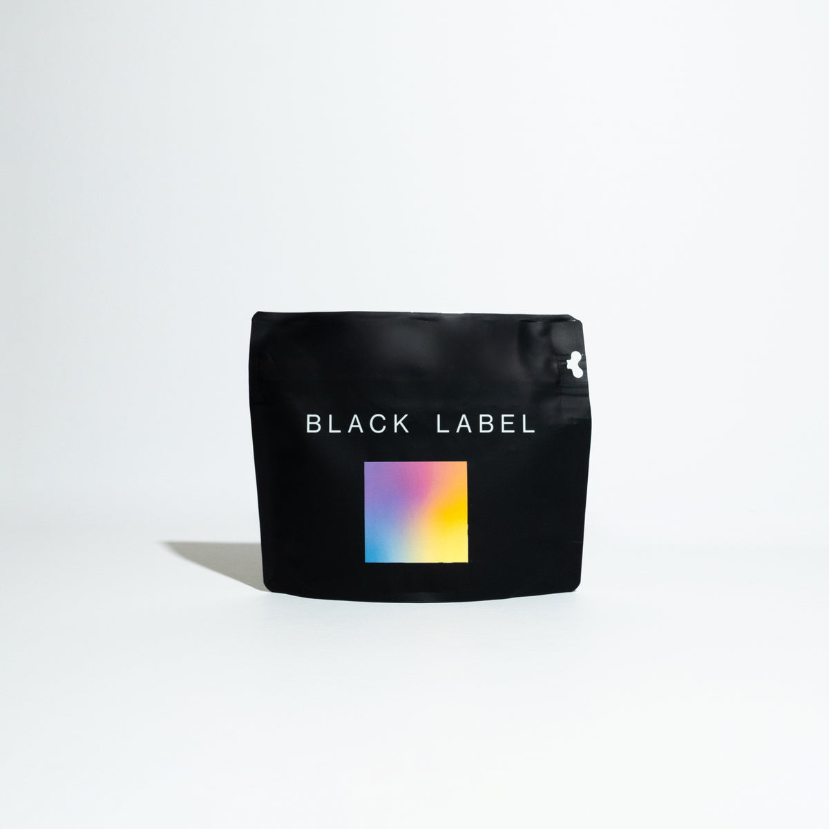 Black bag featuring a colorful square, representing the Jardines del Encanto - Maragesha coffee, a specialty product from Colombian producer Felipe Arcila.