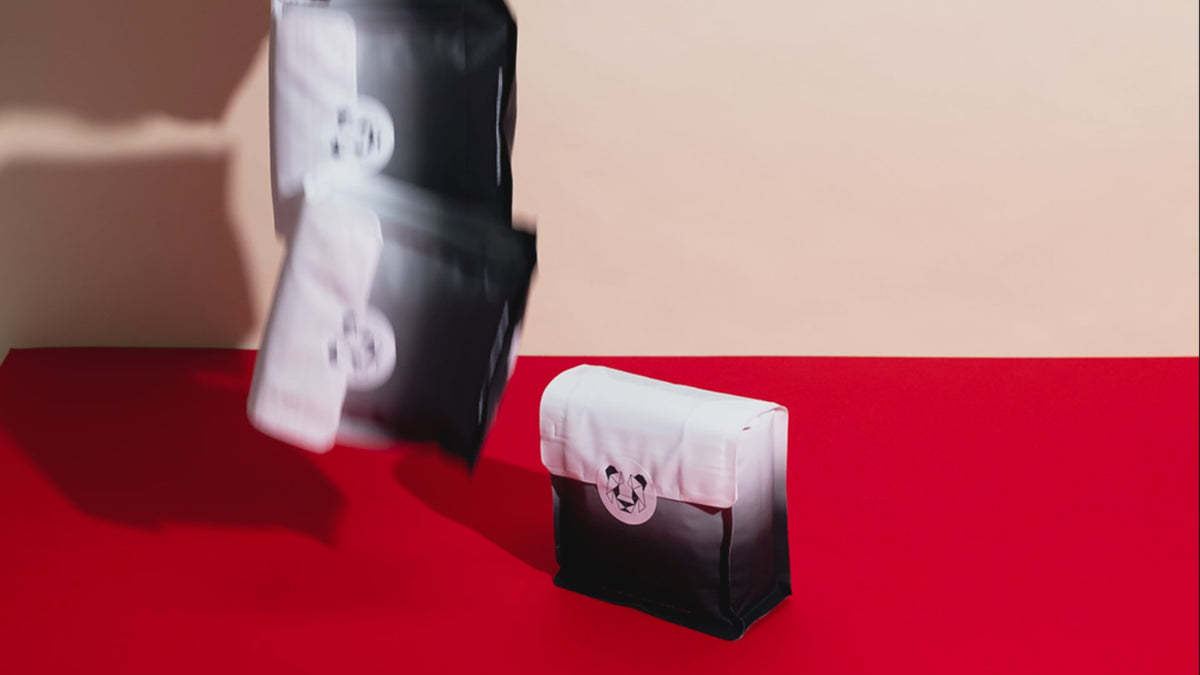  A short video on repeat of several coffee bags being dropped on a backdrop in a pile. 